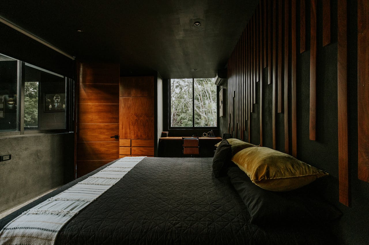  A modern bedroom featuring a striking black wall complemented by warm wooden accents